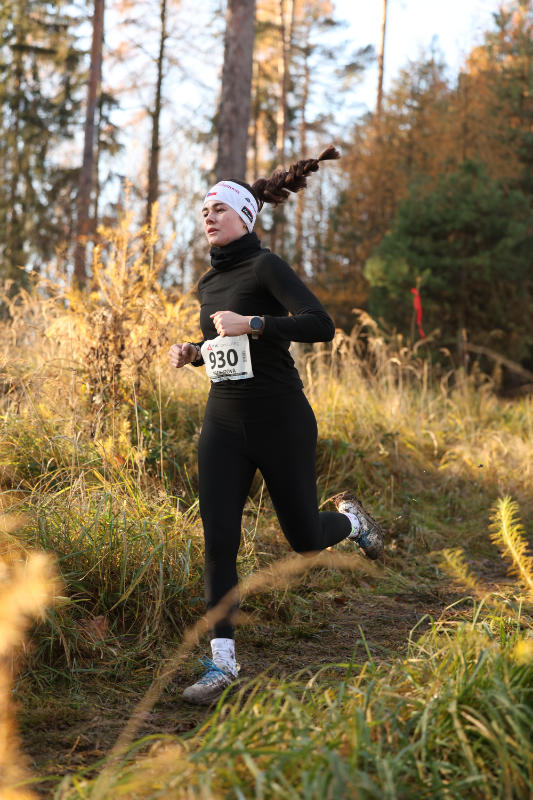 A runner climbs a rocky trail in a winter forest.